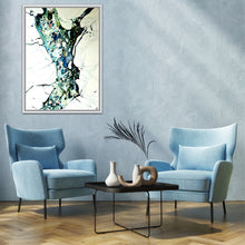 Load image into Gallery viewer, A framed abstract painting hangs on a textured light blue-gray wall above two matching light blue armchairs and a small black coffee table with decorative vases in a styled living room.
