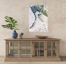 Load image into Gallery viewer, Abstract painting of rock pools along the edge of the ocean in shades of white, blue and green. In situ on a beige wall above a timber sideboard.
